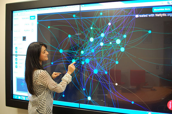 Computer Science PhD student Naureen Nizam demonstrates the "Magic Wall" at the Social Media Lab. The 96-inch screen can display millions of online conversations. PHOTO: Social Media Lab.